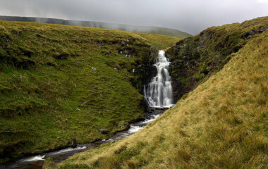 Fototapeta na wymiar Threatening weather over one of a series of waterfalls that roll down the mountains in the Brecon Beacons in South Wales UK 
