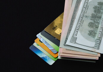 bank plastic credit cards and debit cards and us dollars on a black background. transition from paper money to non-cash and electronic payments and purchases. refusal of paper pulp