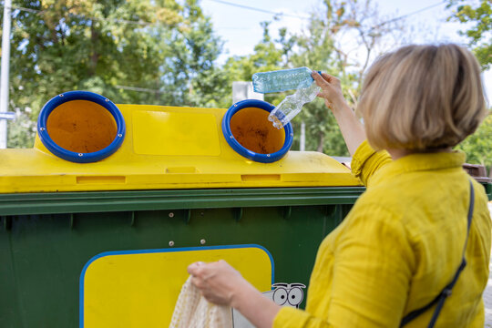 Anonymous woman throwing out trash in yellow bin