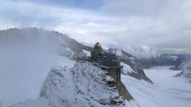 Aerial view of Sphinx Observatory above the Jungfraujoch in Switzerland. Drone footage of snowy glacial mountain peaks in Valais, Switzerland.