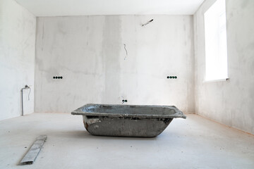 an old bathtub with cement mortar in A room in a house under construction. 