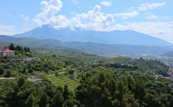buildings on the side of a mountain in small european village town (distant blue hills, trees, nature landscape)