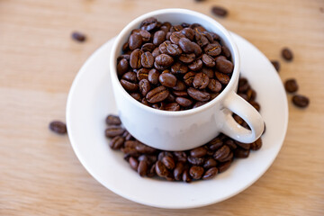 Cup of coffee that full of coffee beans on wooden background with rim light