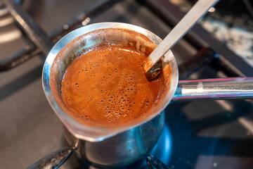 stainless steel turkish Coffee pot on black gas stove ready to boil