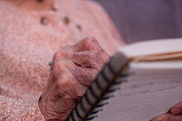 wrinkled hands for elderly person writing notes on his note book