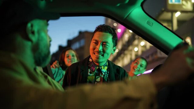 Young and diverse group of friends catching a taxi while on vacation in the city at night