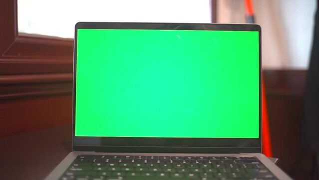 Laptop with green screen in an office.