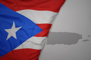big waving national colorful flag and map of puerto rico on the gray background.
