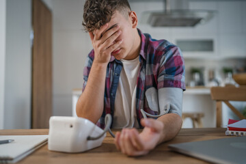 one teenager caucasian man measure check blood pressure at home alone