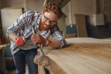Close up of craftsman working with chisel while cutting wooden plank in carpentry workshop