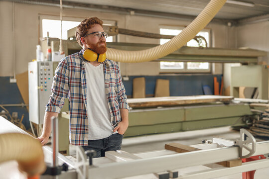 Portrait of carpenter in eyeglasses standing on the background on carpentry workshop