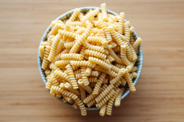 dried fussily pasta in bowl over wooden background