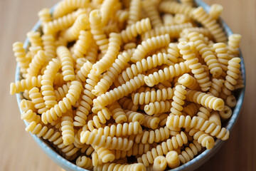 dried fussily pasta in bowl over wooden background