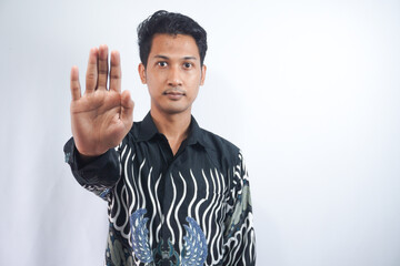 Fototapeta premium Portrait of serious young Asian man showing stop gesture, demonstrating denial sign, rejecting something unwanted isolated on white background
