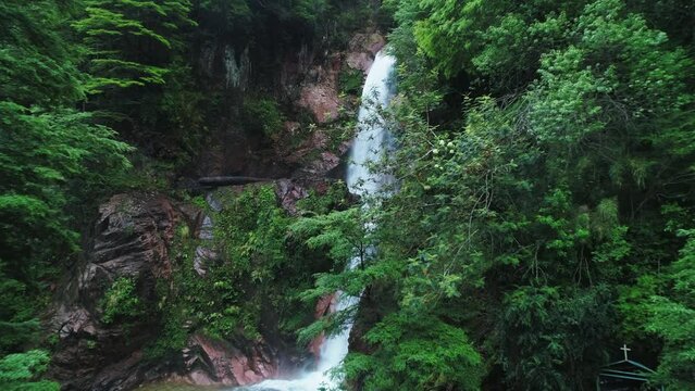 Aerial Forward Shot Of Waterfall From Cliff Amidst Green Plants - Puerto Chacabuco, Chile