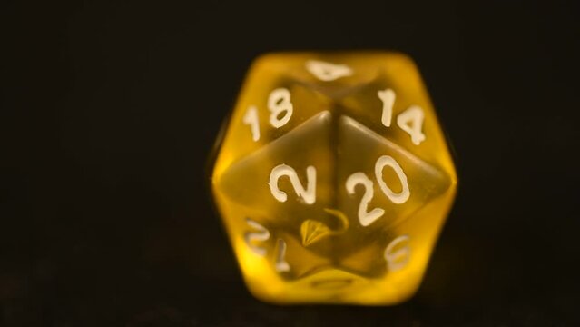 Yellow d20 tabletop board game die rotating tabletop gaming component amber color