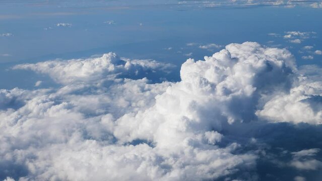 Bird view of white clouds with blue sky background, taken from a high angle on an airplane, 4k slow motion footage.
