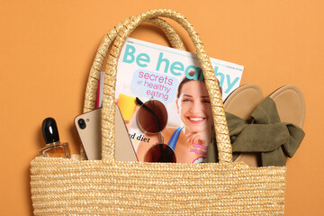 Flat lay composition with wicker bag and other beach accessories on orange background