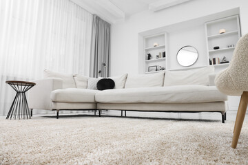 Fluffy carpet and stylish furniture on floor indoors, low angle view