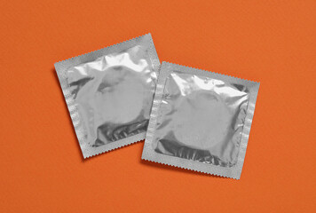 Condom packages on orange background, flat lay. Safe sex