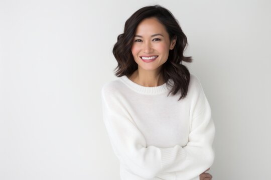 Lifestyle portrait photography of a Vietnamese woman in her 30s wearing a cozy sweater against a white background
