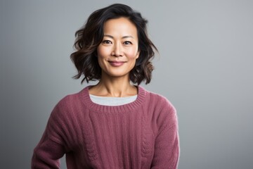 Fototapeta premium Group portrait photography of a happy Vietnamese woman in her 40s wearing a cozy sweater against a white background