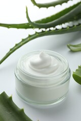 Jar of natural cream and aloe leaves on white background, closeup