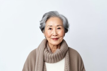 Medium shot portrait photography of a Vietnamese woman in her 70s wearing a cozy sweater against a white background