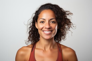 Portrait photography of a happy Peruvian woman in her 30s wearing a sporty tank top against a white background