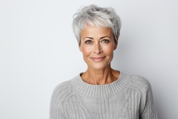 Lifestyle portrait photography of a tender French woman in her 50s wearing a cozy sweater against a white background