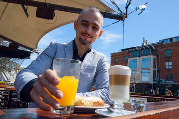 french adult businessman holding glass with orange juice during breakfast in restaurant