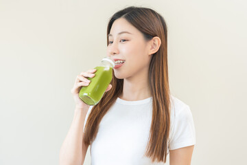 Green detox juice concept, Beautiful asian young woman hand holding vegetable smoothie bottle for diet on background. Happy girl drinking healthy meal food for weight loss. Lifestyle, vegan nutrition.