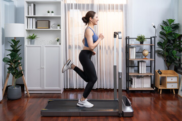 Full length side view of energetic and strong athletic asian woman running running machine at home. Pursuit of fit physique and commitment to healthy lifestyle with home workout and training. Vigorous - obrazy, fototapety, plakaty
