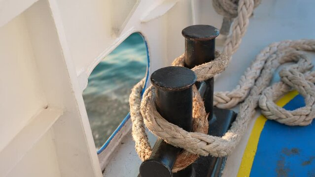 Close up of nautical rope with sailing knot on the bitts for boating and mooring vessel. Motion water surface in the background