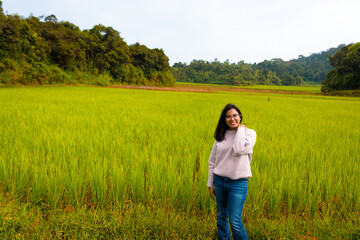 Enjoying the nature. Beautiful and young Indian woman  enjoying the fresh air in green paddy farm. 