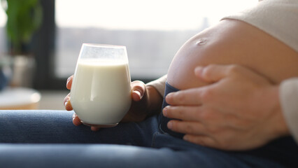 Pregnant woman drinking milk at home. Staying hydrated and consuming dairy products while pregnant....
