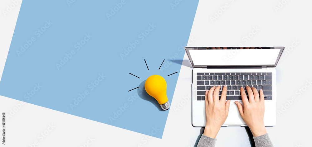 Poster person using a laptop computer and a light bulb - flat lay