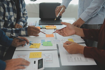 Close up ux developer and ui designer brainstorming about mobile app interface wireframe design on table with customer breif and color code at modern office.Creative digital development agency - obrazy, fototapety, plakaty