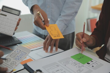 Close up ux developer and ui designer brainstorming about mobile app interface wireframe design on...