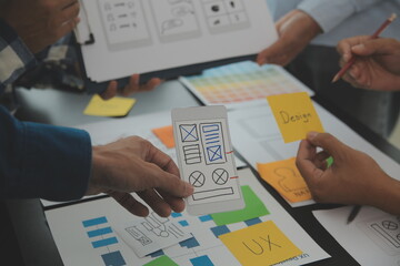 Close up ux developer and ui designer brainstorming about mobile app interface wireframe design on...