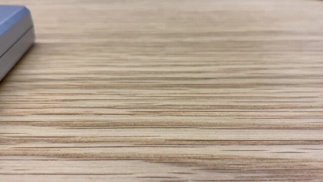 room insideWooden table surface textured close up view. Air conditioner remote control on table. Furniture and room interior concept 