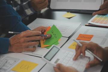 Close up ux developer and ui designer brainstorming about mobile app interface wireframe design on...