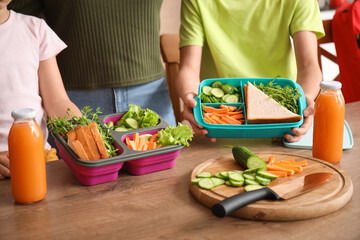 Mother and her little children with school lunch boxes in kitchen, closeup