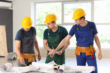 Team of male builders working with house plan in room