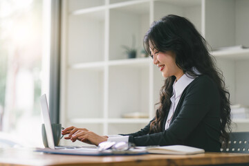 Image of young beautiful joyful woman smiling while working with laptop in office.