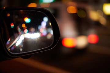 車のサイドミラーから見た夜の都市の夜景の風景