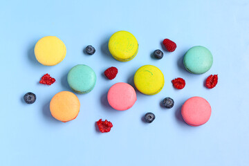 Different sweet macaroons and berries on blue background