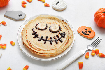 Composition with funny Halloween pancakes and sweets on light background