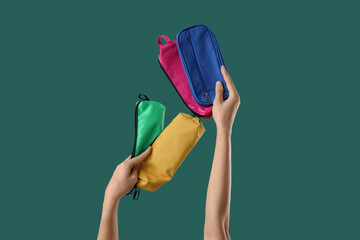 Hands with pencil cases on color background