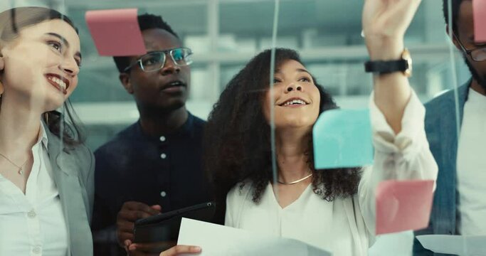 People, writing and sticky note on glass, wall or planning with creative teamwork and brainstorming with information. Group, collaboration and talking of strategy or meeting on board in London office
